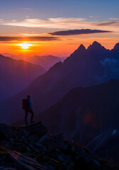Fototapeta premium A solitary male hiker, contemplative and awestruck, stands on a mountain peak, gazing at a vibrant sunset over a dramatic alpine range