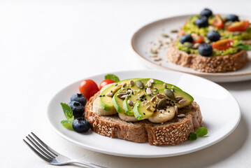 Avocado toast with banana, sunflower seeds, pumpkin seeds, sesame seeds, blueberries and tomatoes, Healthy food 
