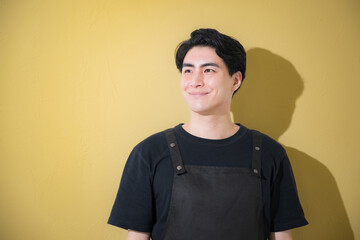 バイトや接客業などエプロンを着た男性のイメージ　背景黄色