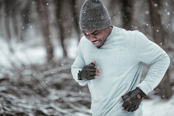 Man jogging in snow during intense winter workout in forest trail
