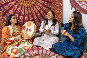 Women holding cocoa ceremony with shamanic drum and mandala tapestry