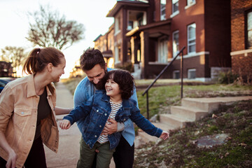 Happy family walking and playing together in front of their home at sunset