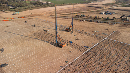 Aerial closed photo  of construction site: installing vertical drains. An excavator with wick drain installation attach. © Adhitya