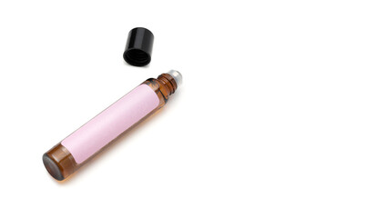Open amber glass roll-on bottle with pastel label and black cap on white background. Concept of...