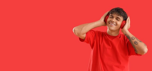 Happy man in headphones listening to music on red background with space for text