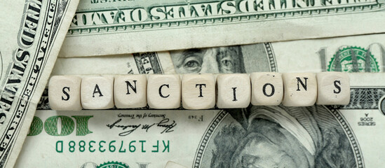 Word SANCTIONS on dollar banknotes, closeup