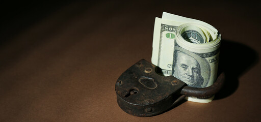 Dollar banknotes with lock on dark brown background. Sanctions concept