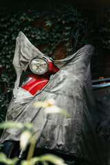 Red Scooter Covered by an Old Tarp in a Green Outdoor Setting