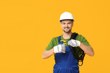 Portrait of male electrician with crimper and wires on yellow background