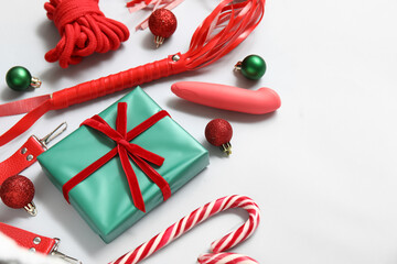 Different sex toys with Christmas balls, gift box and candy canes on white background