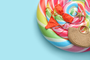 Swimming mattress in shape of candy with bikini and mobile phone on blue background. Top view