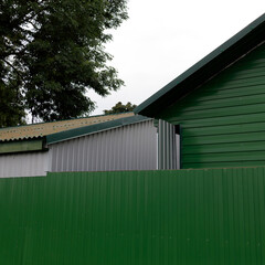 Contemporary structures with green and gray metal siding and roofing stand behind a corrugated...