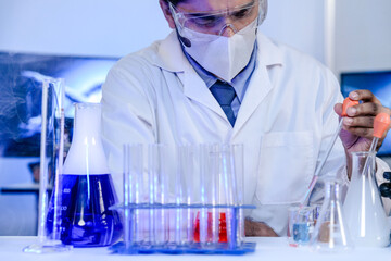 An Indian scientist in a lab coat carefully examines a sample during a pharmaceutical research and...