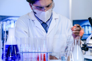 An Indian scientist in a lab coat carefully examines a sample during a pharmaceutical research and development process. Concept for scientific discovery and innovation.