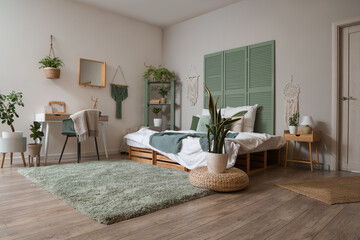 Interior of stylish bedroom with cozy bed, workspace and houseplants