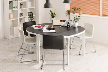 Interior of light office with desk, shelf unit and plants