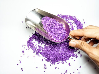 purple plastic masterbatch, polymer carries colorful pigments with small scoops poured into a white...