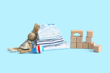 Stack of baby clothes with toys on blue background