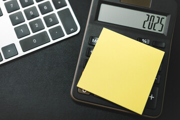 Blank Sticky Note on Calculator and forecast for finances in 2025. Money, Budget, tax, investment, financial and savings. calculator with 2025 numbers.