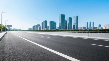 Fototapeta premium Empty Highway Leading to Modern Cityscape Under Clear Blue Sky