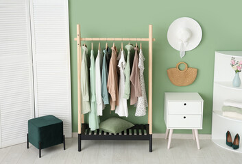 Interior of stylish dressing room with clothes rack, folding screen and shelving unit