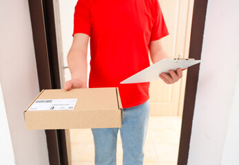Male courier with parcel and clipboard at doorway