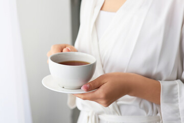 Woman with cup of tea at home, closeup