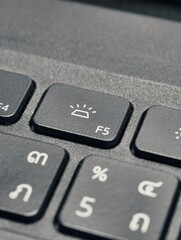 Illuminating Function: An abstract close-up presents a keyboard featuring the F5 key, cleverly highlighting the brightness function with a sharp focus and monochrome palette.