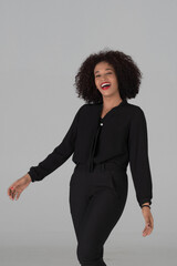  A lively photo of a stylish woman with a wide, spontaneous laugh and an open, joyful posture against studio on gray background.