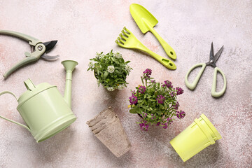 Pots with flowers and gardening tools on beige grunge background
