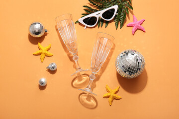 Disco balls with champagne glasses, sunglasses and starfishes on orange background