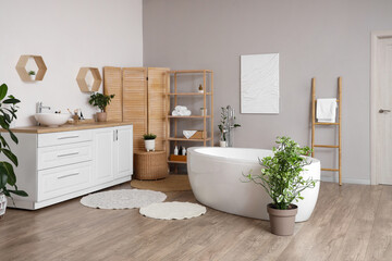 Chest of drawers with sink, bathtub and folding screen in interior of light bathroom