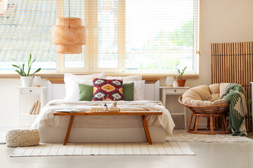 Big comfortable bed, bench and wooden folding screen in interior of bedroom
