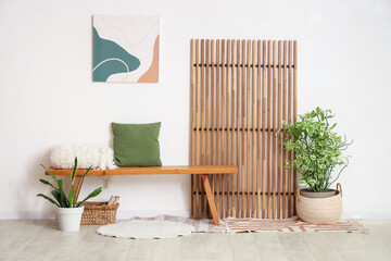 Interior of stylish room with bench, houseplants and wooden folding screen
