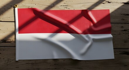 Fototapeta premium Indonesian flag, featuring red and white horizontal stripes, displayed on a wooden surface with shadows.