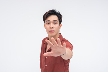 A surprised young Asian man raising his hand urgently to signal ‘wait,’ looking alarmed....