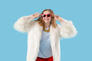 Fashionable young woman dancing on blue background