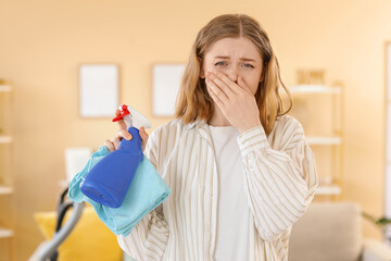 Young woman suffering from allergy while cleaning flat