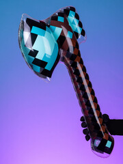 Close-up of a blue inflatable axe toy in pixel style on purple and blue background