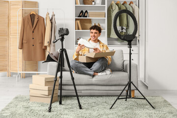 Male blogger with new sneakers recording video on sofa at home