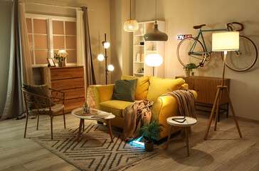 Interior of living room with yellow sofa, armchair and glowing lamps in evening
