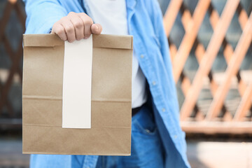 Woman with paper bag outdoors, closeup. Food delivery service