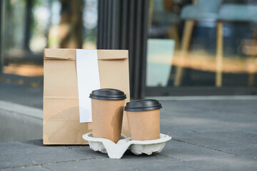 Paper bag with coffee cups on street. Food delivery service
