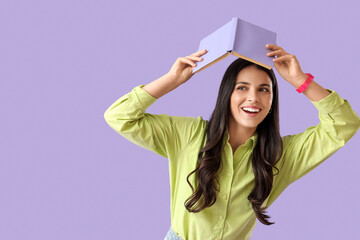 Beautiful woman with book on lilac background