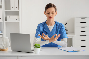 Female doctor meditating at table in clinic
