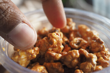 Enjoying caramel popcorn from a plastic container