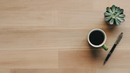 Fresh start with coffee, succulent, and pen on wooden desk for creative work