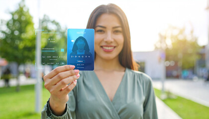 Technology and Identity: A modern woman holds up a transparent ID card, representing digital identity and futuristic technology in a contemporary outdoor setting.