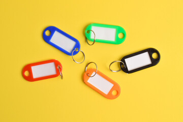 Colorful plastic key tag isolated on yellow background. Top view, flat lay