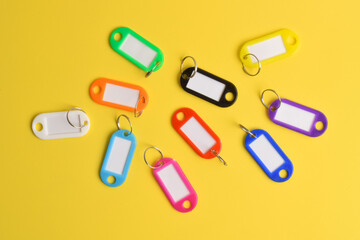 Colorful plastic key tag isolated on yellow background. Top view, flat lay